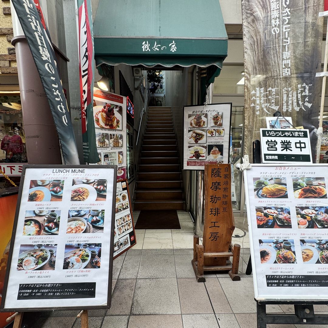 なや通りから見た入口。緑の日よけに「彼女の家」と書かれていて、脇の階段から2階へ上がる